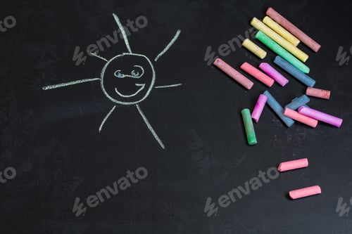 Preview: colored chalks, black blackboard with drawings of the sun
