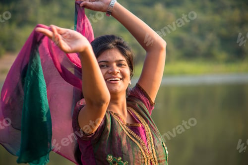 Preview: Young happy Indian girl playing with her pink scarf at outdoor.