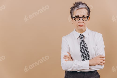 Preview: Senior business woman standing with arms crossed on beige background
