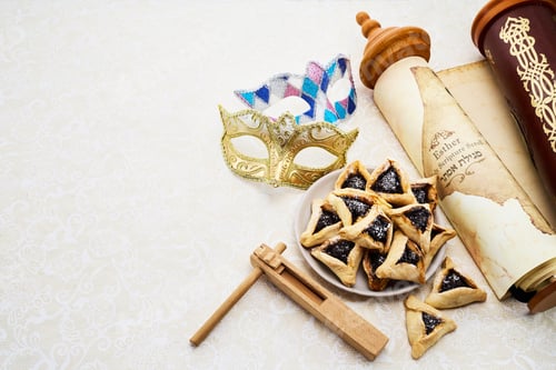 Preview: Purim Celebrations. Golden mask, scroll, gragger, and hamantaschen on decorative background