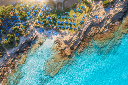 Preview: Aerial view of sea bay, sandy beach with umbrellas at sunset