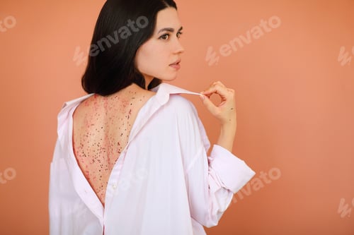 Preview: Back view of young female in white clothes revealing back with shiny mask against brown background