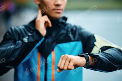 Preview: Close up of sportsman using fitness tracker and checking his heart rate outdoors.