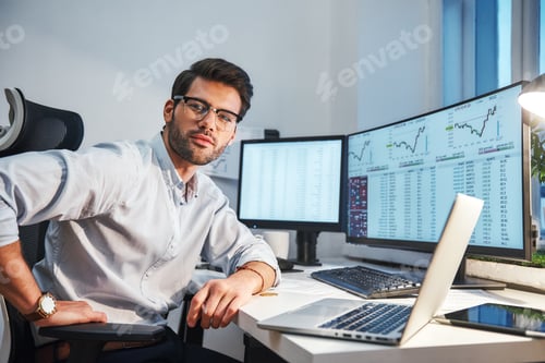 Preview: Confident and smart. Young trader or businessman in eyewear and formal clothes is looking at
