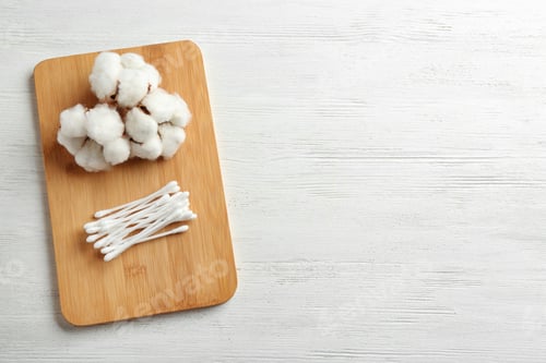 Preview: Board with cotton swabs and flowers on white wooden background, top view. Space for text