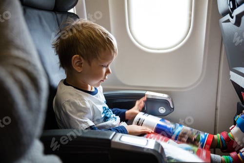 Preview: Little boy reading magazine while on board of airplane