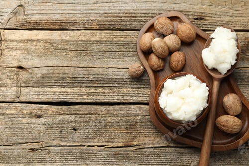 Preview: Natural shea butter and nuts on wooden table, top view. Space for text
