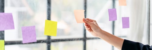 Preview: A hand is holding a yellow and purple sticky note