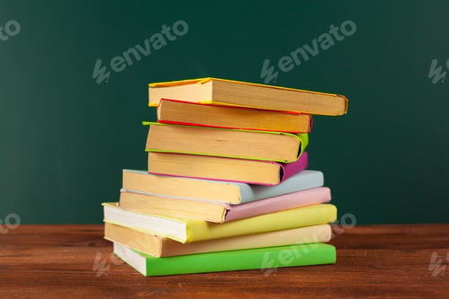 Preview: Stacked books in bright colors on a wooden table against a green background