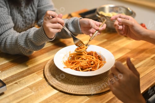 Preview: Close up of young couple sharing a plate of spaghetti during the holiday season
