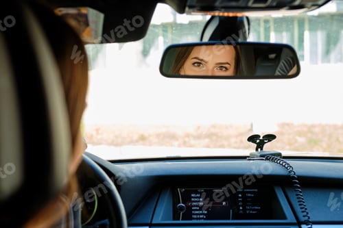 Preview: Reflection of female eyes in rearview mirror of a car