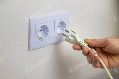 Preview: The man plugs in the cord. Selective focus.