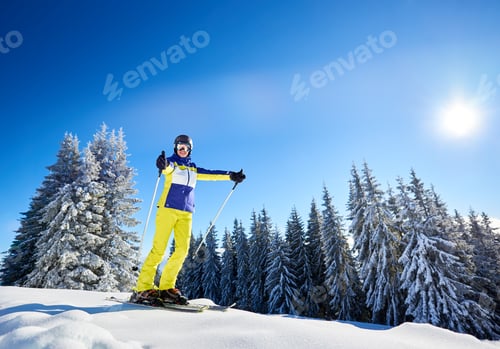 Preview: Happy woman posing on skis before skiing. Sunny day at ski resort.