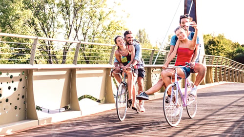 Preview: Young milenial friends having fun riding bike at city park bridge