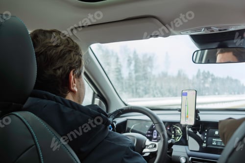 Preview: Driver follows GPS route on smartphone mount inside modern car on snowy highway