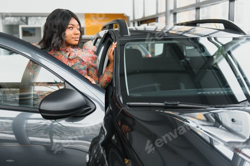 Preview: beautiful young african woman buying a car at dealership