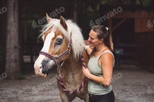 Preview: Woman petting a beautiful colorful horse, holding him for a leash, going horse back riding