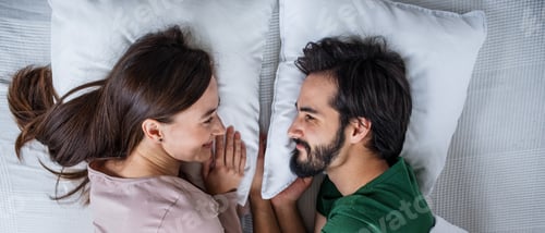 Preview: Top view of young couple in love lying on bed indoors at home.