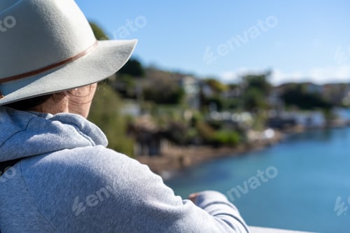 Preview: view from behind person lady in wide brimmed hat looking at the ocean