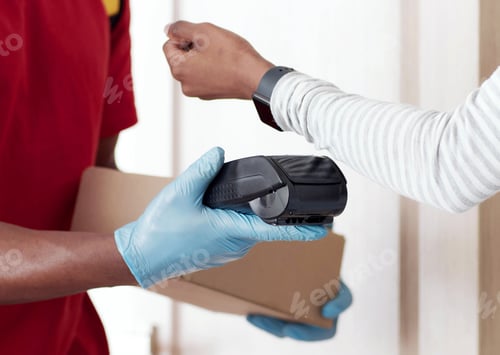 Preview: Close up of black woman paying for order with smartwatch, taking box from courier in protective