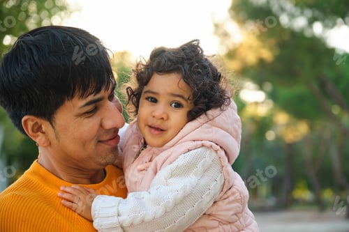 Preview: Happy Ecuadorian father holding her one year old daughter in a park.