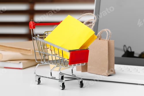 Preview: Online shopping concept. Shopping cart, laptop on the desk