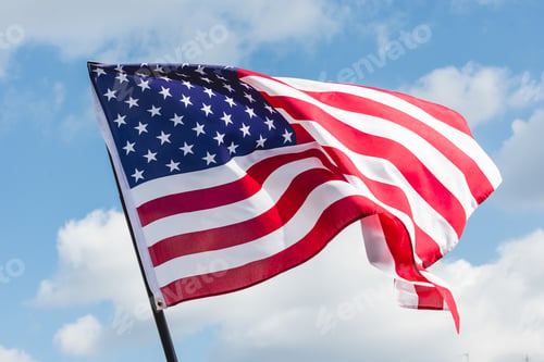Preview: low angle view of stars and stripes on american flag against blue sky
