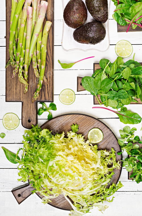 Preview: Green herbs, asparagus and black avocado on a white wooden background. Top view. Flat lay