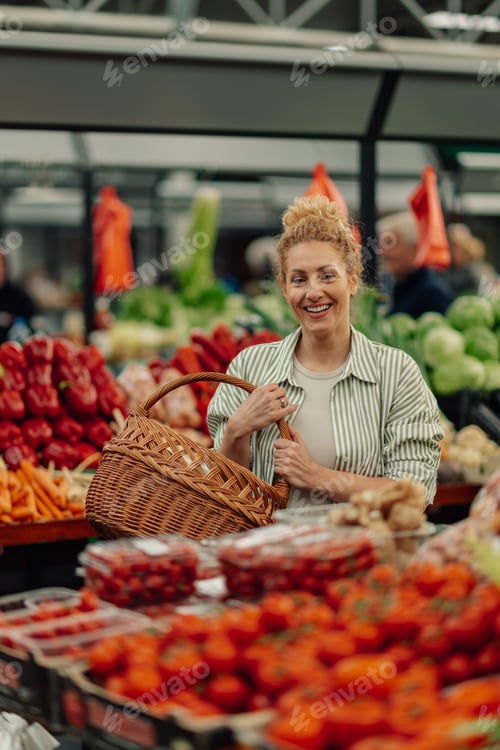 Preview: Portrait of happy shopper with basket standing at farmers market.