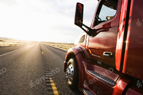Preview: Close up side view looking forward of a commercial truck on a highway at sunset.
