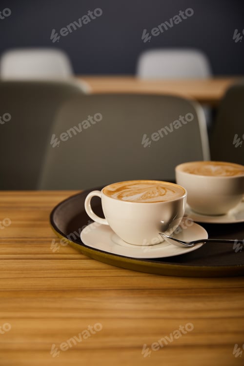 Preview: selective focus of cappuccino in white cups on black tray