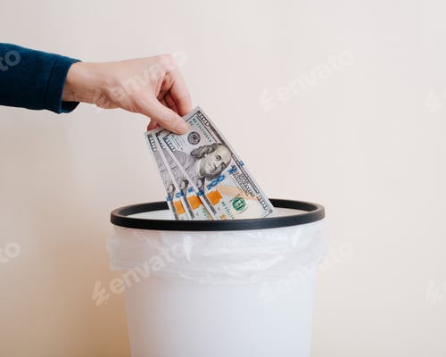 Preview: Close-up hand throws money, one hundred dollar bills into trash can