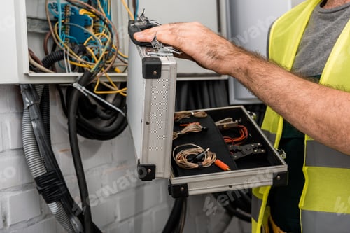 Preview: cropped image of electrician holding toolbox near electrical box in corridor