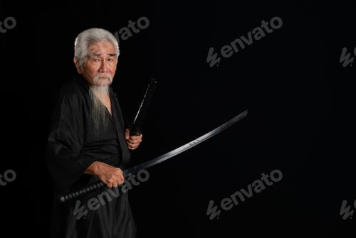 Preview: Senior Japanese samurai with katana sword on black background, studio shot
