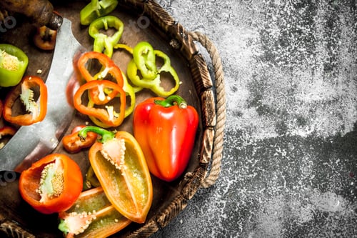 Preview: chopped sweet pepper in a wooden tray with a knife.