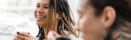 Preview: Smiling Woman with Braids Enjoying Beverage Indoors