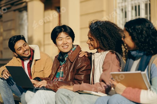 Preview: Smiling students with laptop is studying outdoors sitting near university. Education concept