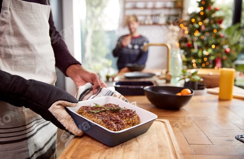 Preview: Close Up Of Man Taking Vegetarian Nut Roast Out Of Oven For Christmas Dinner