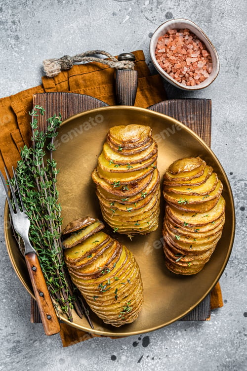 Preview: Baked Hasselback Potato with Fresh thyme and rosemary. Gray background. Top view