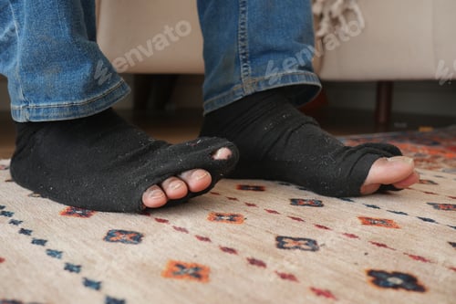Preview: men feet with dirty socks while sitting on sofa