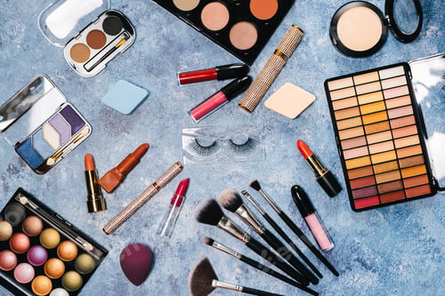 Preview: makeup brushes, decorative cosmetics, false eyelashes on a blue background. the view from the top