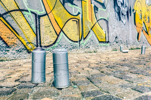 Preview: Detail of aerosol spray can at colorful graffiti on wall