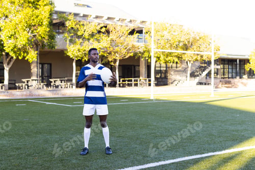 Preview: African American young male athlete holding rugby ball, wearing sportswear, copy space