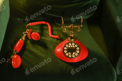 Preview: Retro red phone with brass components, set on soft green velvet.