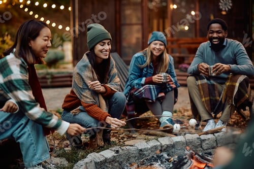 Preview: Happy woman and her friends roasting marshmallows on fire in the backyard.