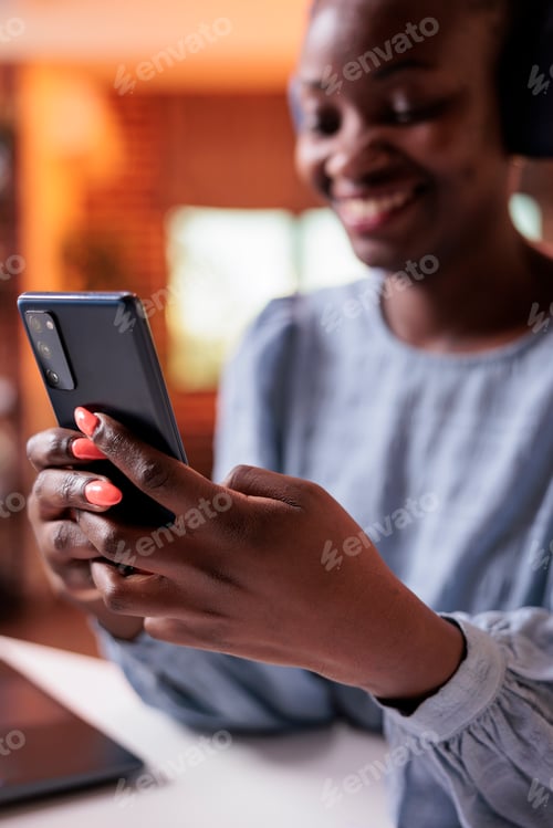Preview: African american woman in headphones holding mobile phone