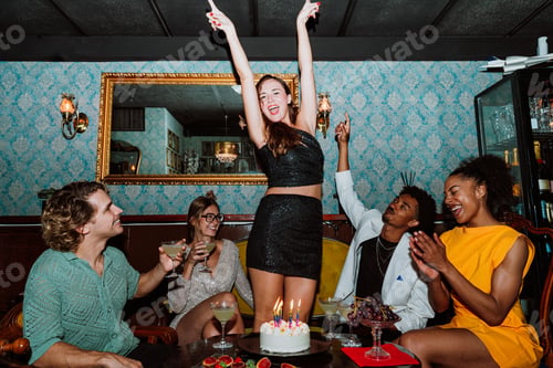 Preview: Friends celebrating birthday party with cake and cocktails