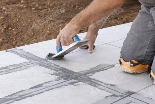 Preview: Craftsman filling tile joints with grout using a float, hand closeup, building construction detail
