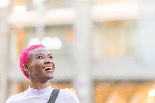 Preview: Beauty young african woman looking up to the sky while smiling outdoors