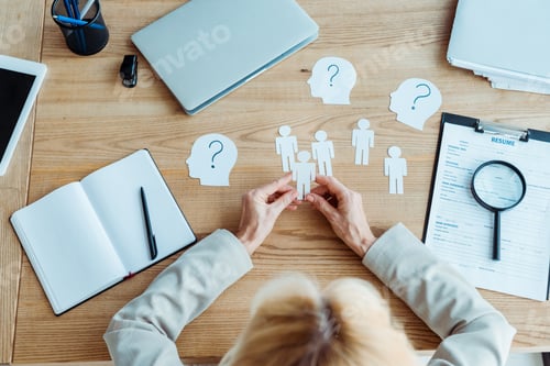 Preview: cropped view of woman holding paper human shapes near table